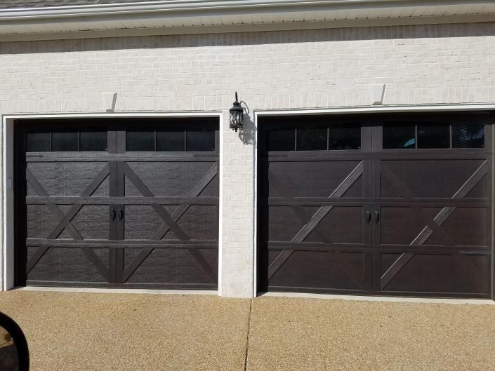 Two dark brown garage doors on a beige stucco building facade