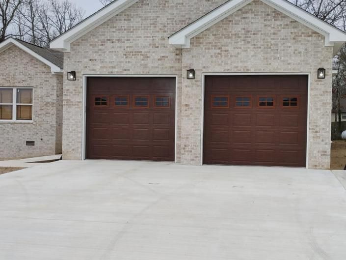 Two-car garage with brown doors on a brick house and a wide concrete driveway