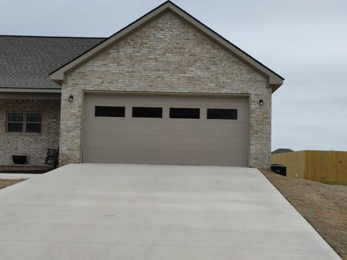 Stone house with a beige garage and a wide concrete driveway