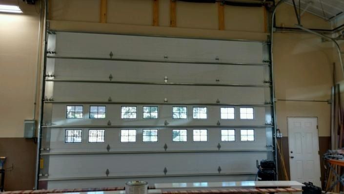 Large industrial roll-up garage door with small windows inside a warehouse or workshop.