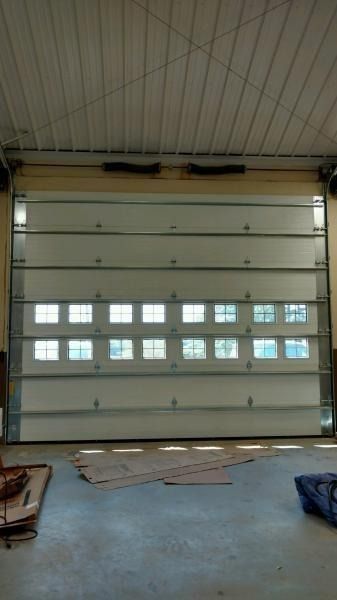 Closed gray garage door with small windows in a workshop or warehouse.
