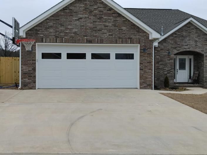 Suburban brick house with a white two-car garage and wide concrete driveway