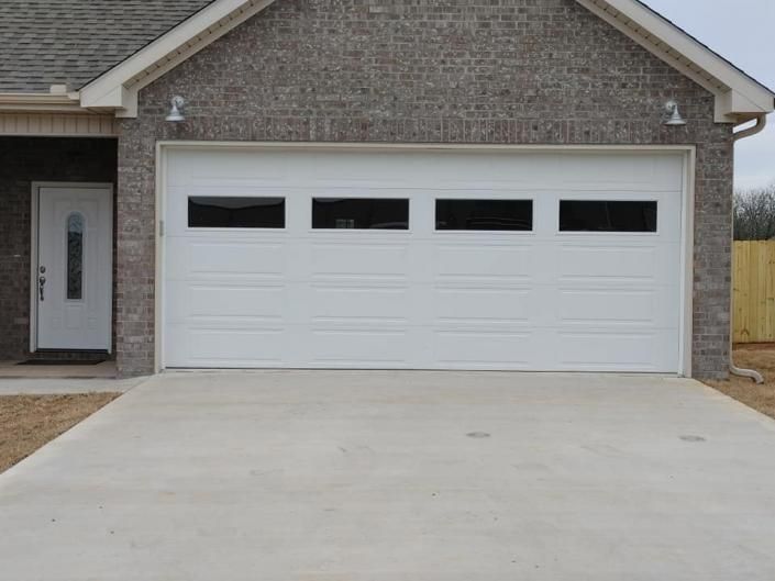 Single-car garage with white door and concrete driveway on a brick house exterior
