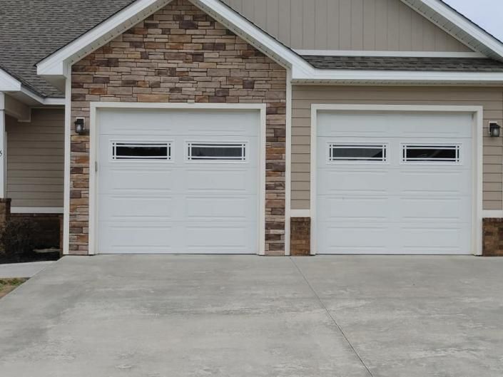 Suburban house exterior with two white garage doors and a concrete driveway