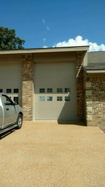 Residential garage with a white door, brick exterior, and a parked silver vehicle on the left.