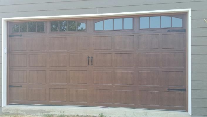 Brown double garage door with small window panes along the top on a light-colored exterior wall