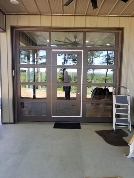 Glass double doors at an entrance with a step ladder and dark doormats nearby