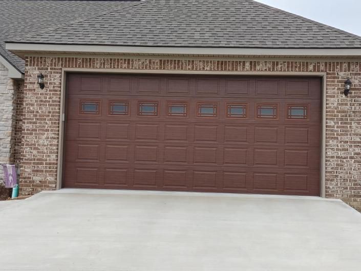 Brick house garage with a brown double door and concrete driveway