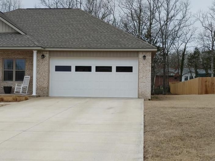 Suburban house with a two-car garage, concrete driveway, and leafless trees in winter.