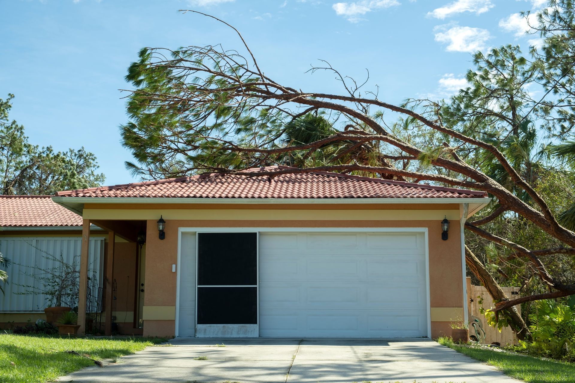 Single-story house with a red roof and garage, with a tree leaning over the driveway