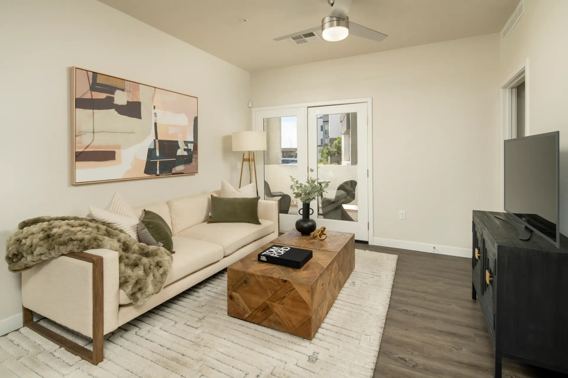 Modern living room with a sofa, coffee table, TV, and abstract art at Lumina Mountain Vista in Mesa, AZ.