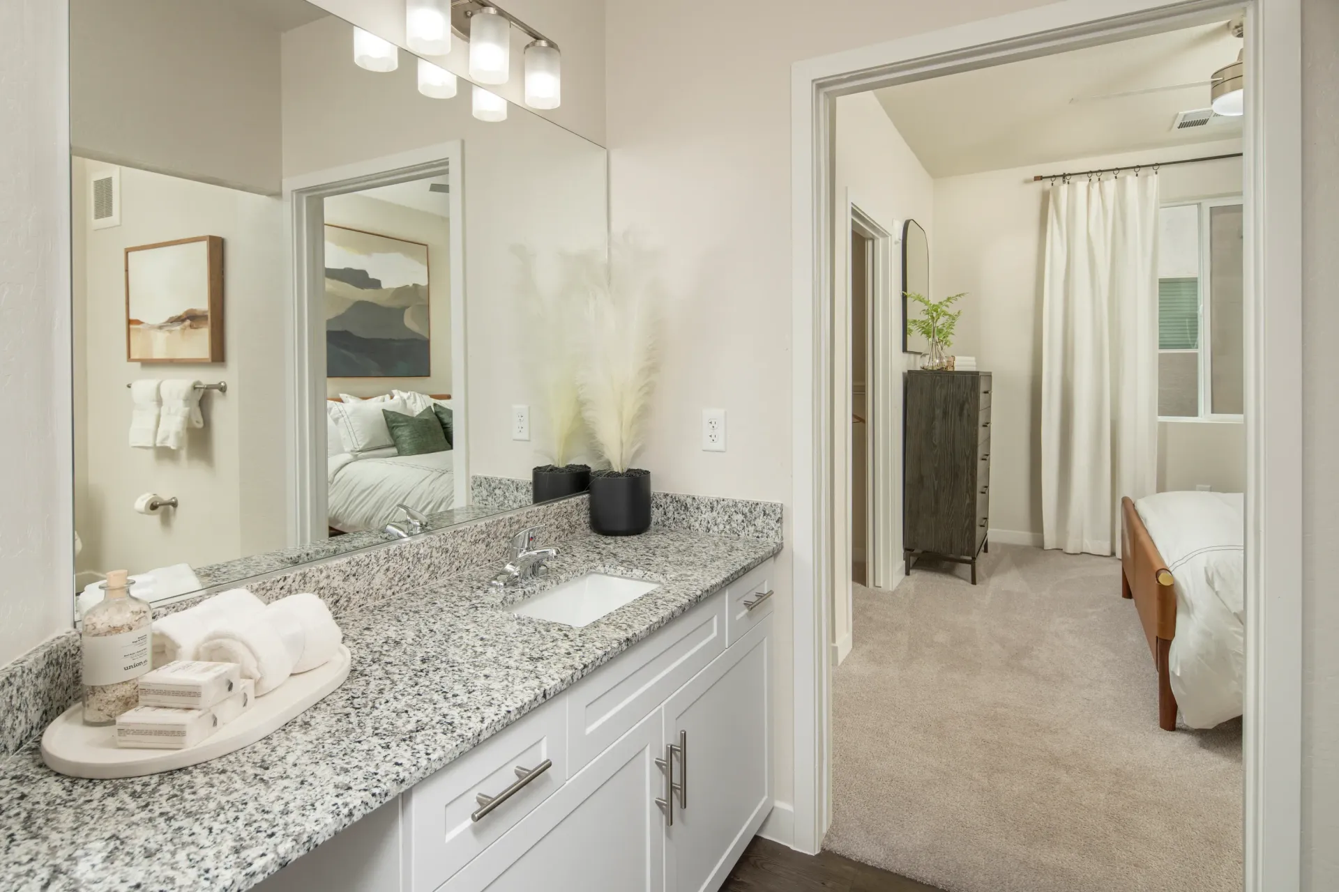 Bathroom vanity with granite countertop and sink, reflection shows bedroom at Lumina Mountain Vista in Mesa, AZ.