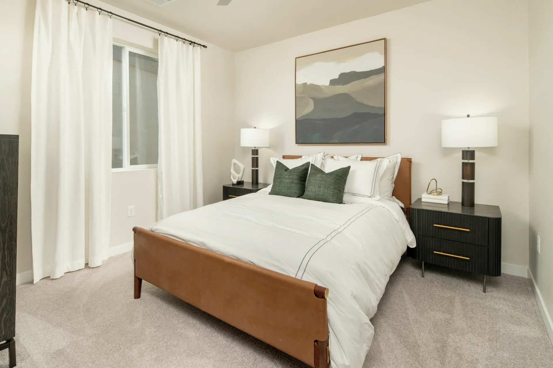 A comfortable bedroom with a queen-size bed, white bedding, and green accent pillows at Lumina Mountain Vista in Mesa, AZ.