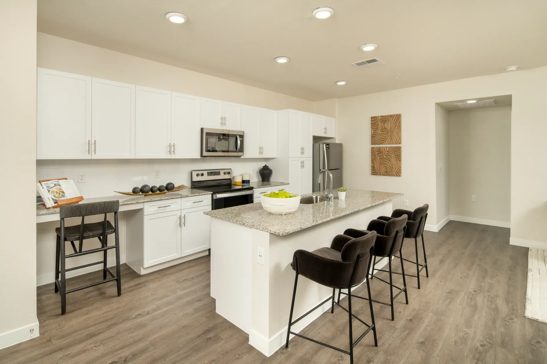 Modern kitchen with white cabinets, granite countertops, stainless steel appliances, and island with bar stools at Lumina Mountain Vista in Mesa, AZ.