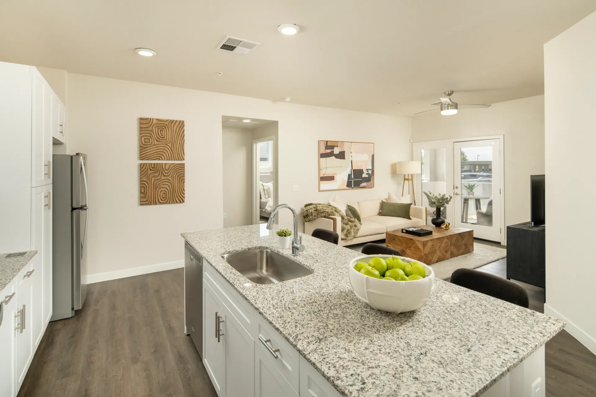 Kitchen island with sink and living room in background at Lumina Mountain Vista in Mesa, AZ.