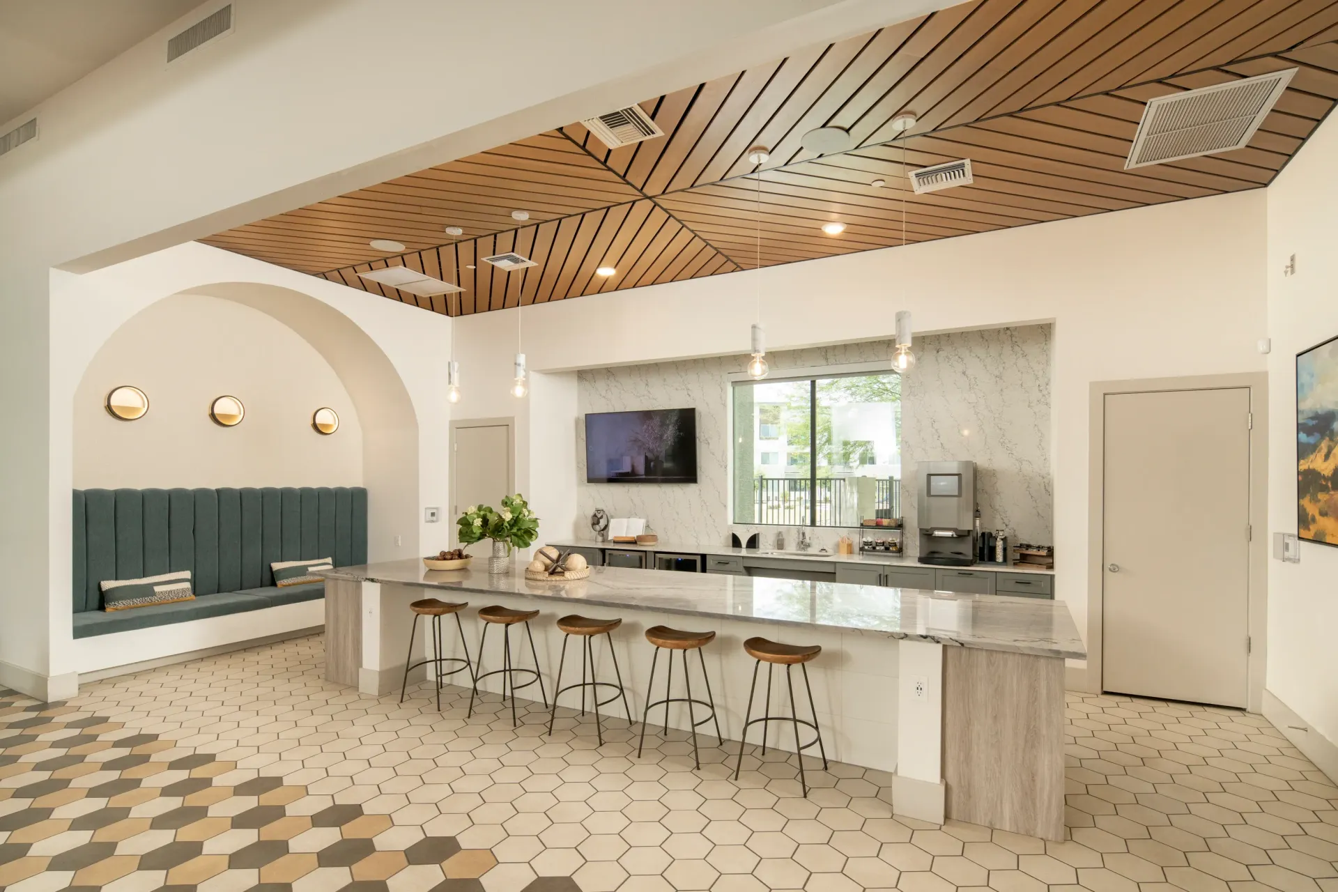 Modern communal kitchen area with island seating and a built-in banquette at Lumina Mountain Vista in Mesa, AZ.