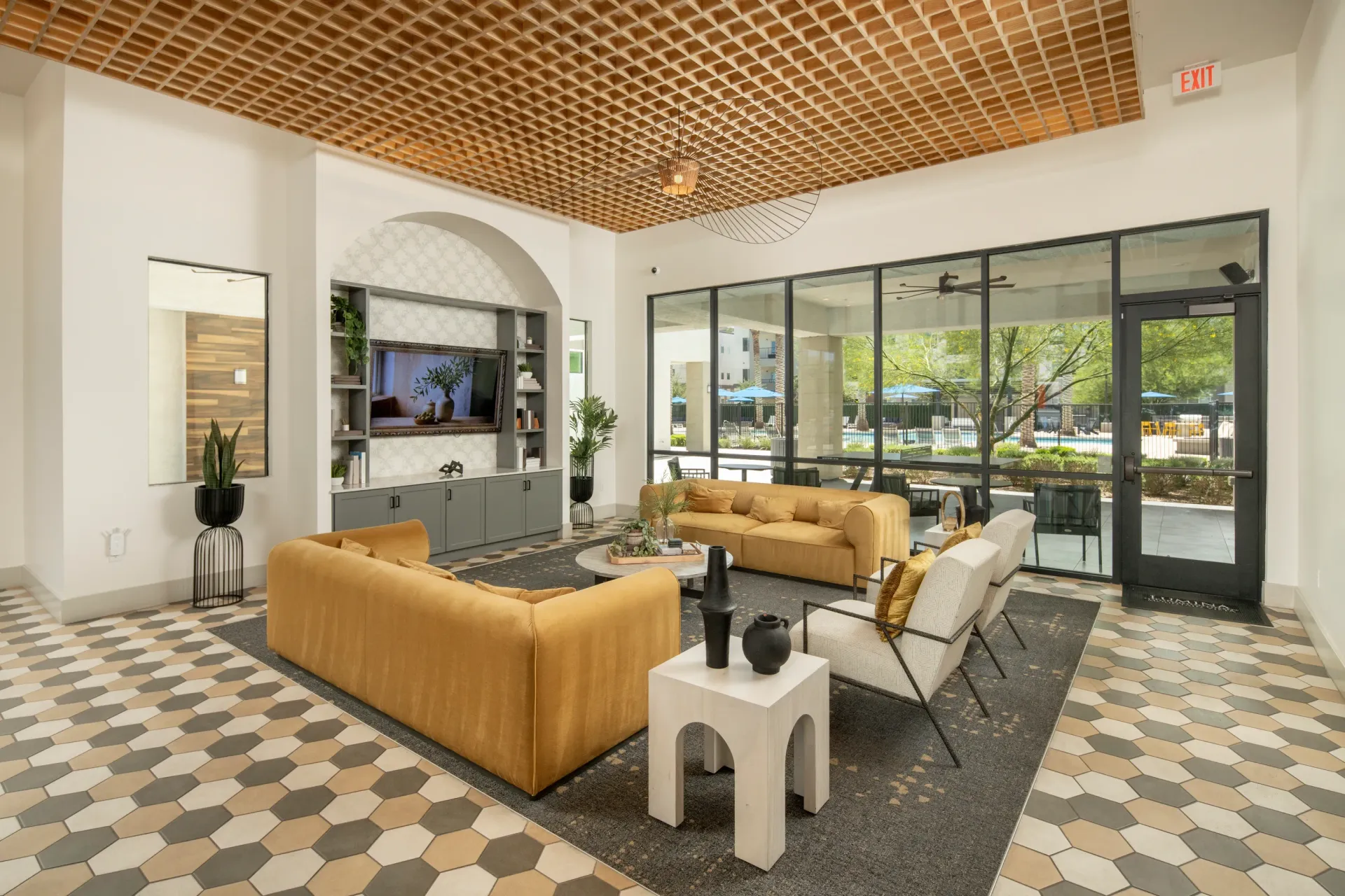 Modern lounge area with yellow sofas and chairs, view of pool area through large windows at Lumina Mountain Vista in Mesa, AZ.