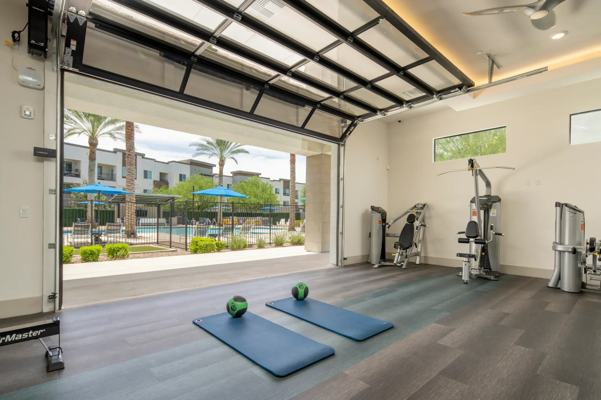 Gym with view of pool and apartment buildings at Lumina Mountain Vista in Mesa, AZ.