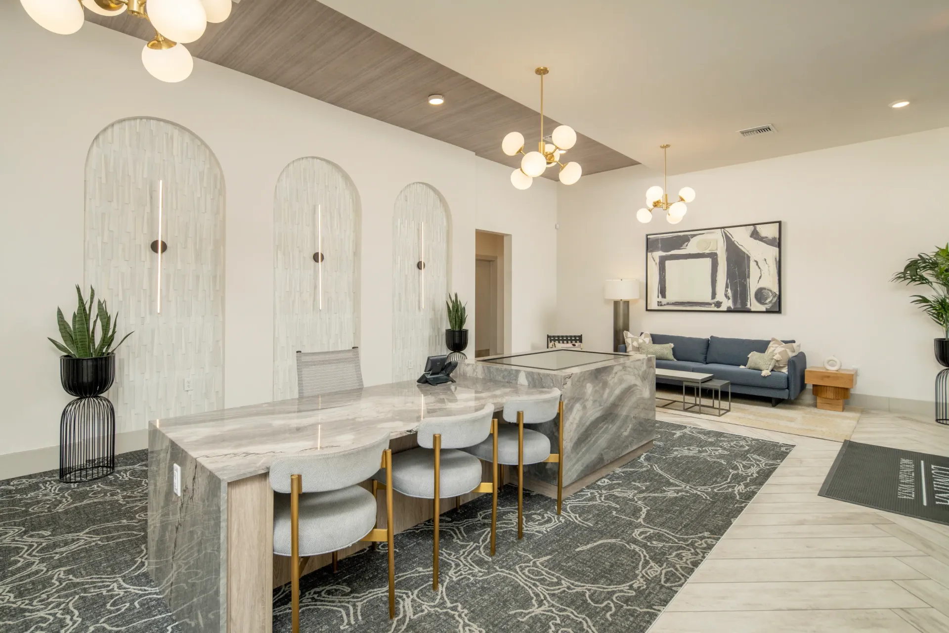 Modern leasing office reception desk with gray chairs and marble countertop at Lumina Mountain Vista in Mesa, AZ.
