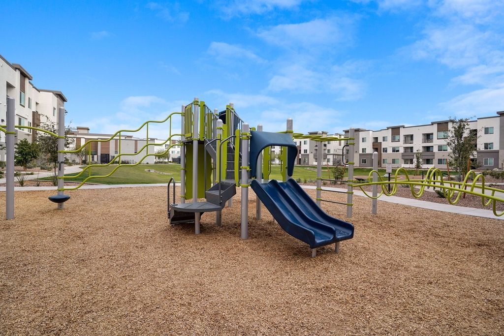 Playground with blue slide and green climbing structures in a residential community.