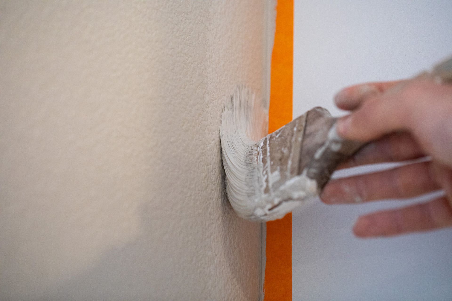 A person is painting a wall with a paint brush.