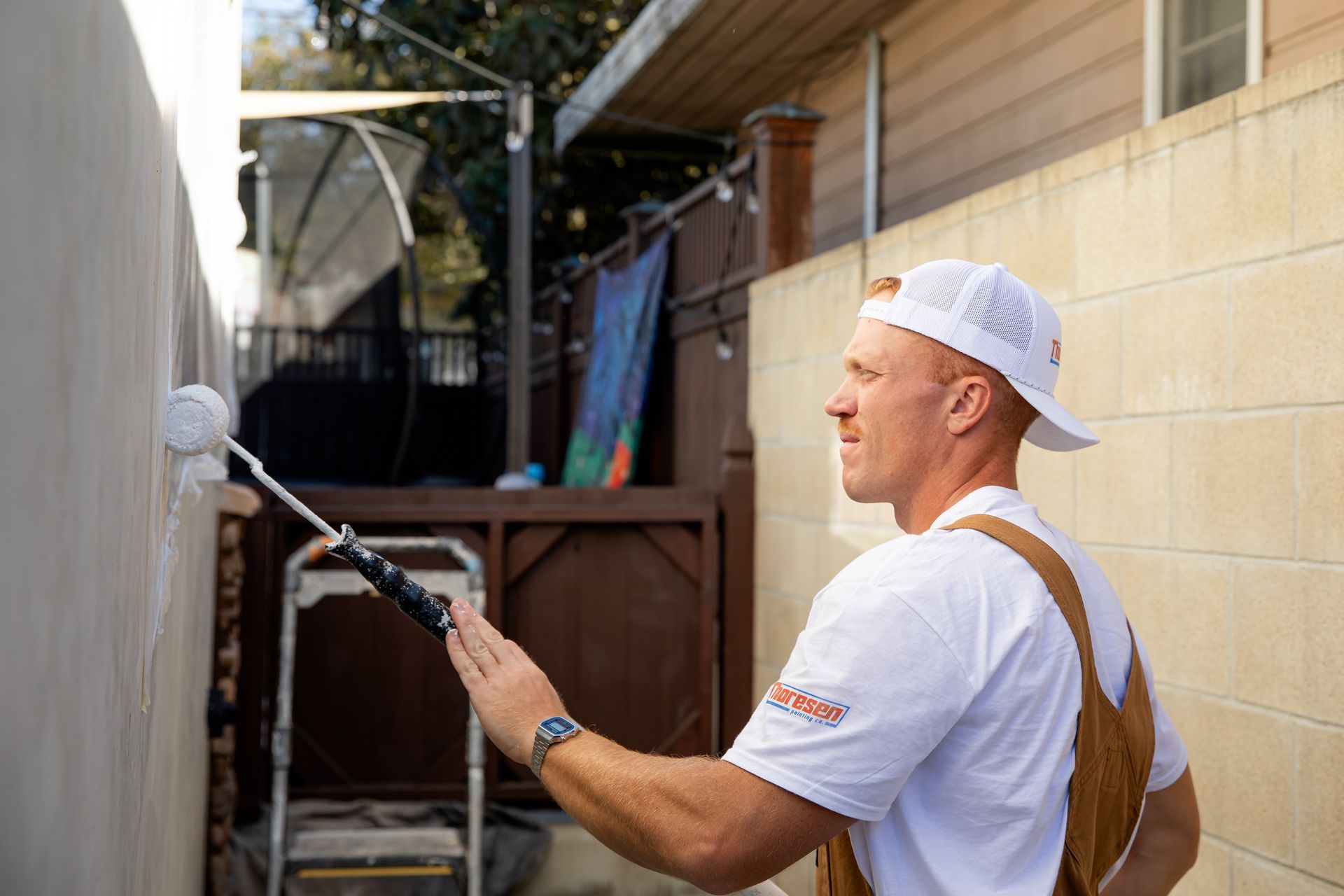 A man is painting a wall with a paint roller.