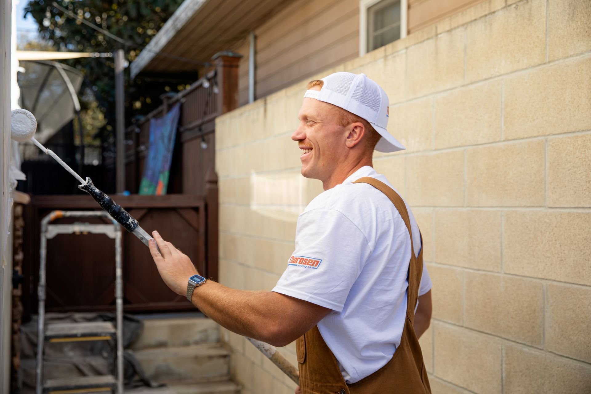 A man is painting a brick wall with a paint roller.