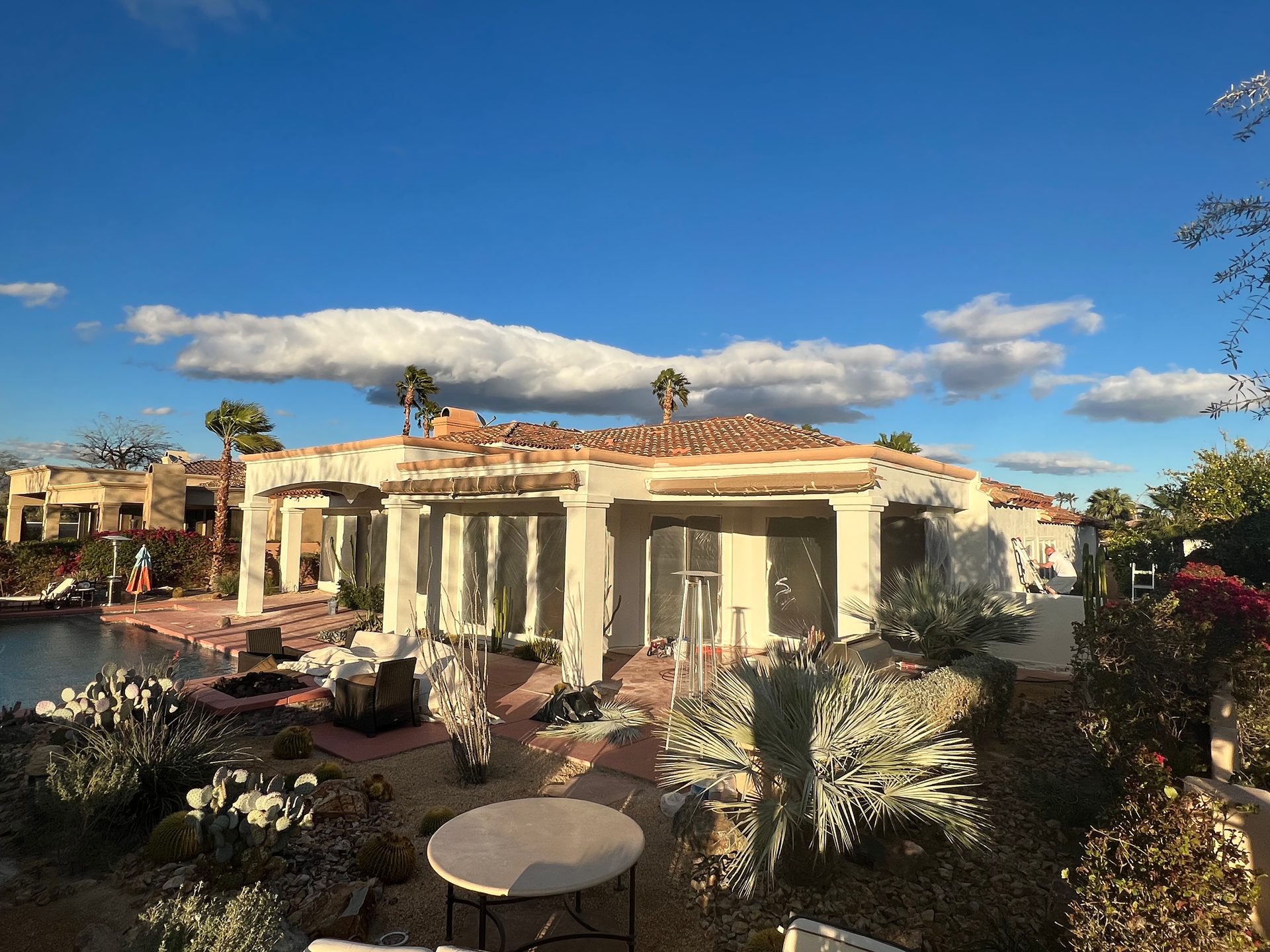 A large white house with a pool and a table in front of it.