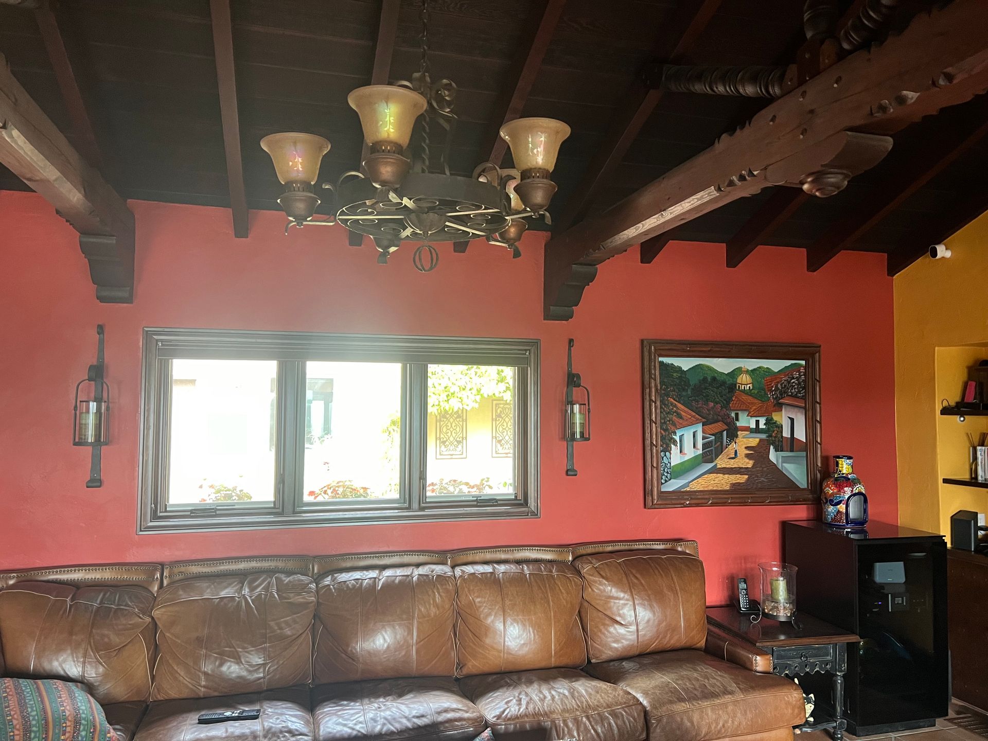 A living room with a brown leather couch and a chandelier hanging from the ceiling.