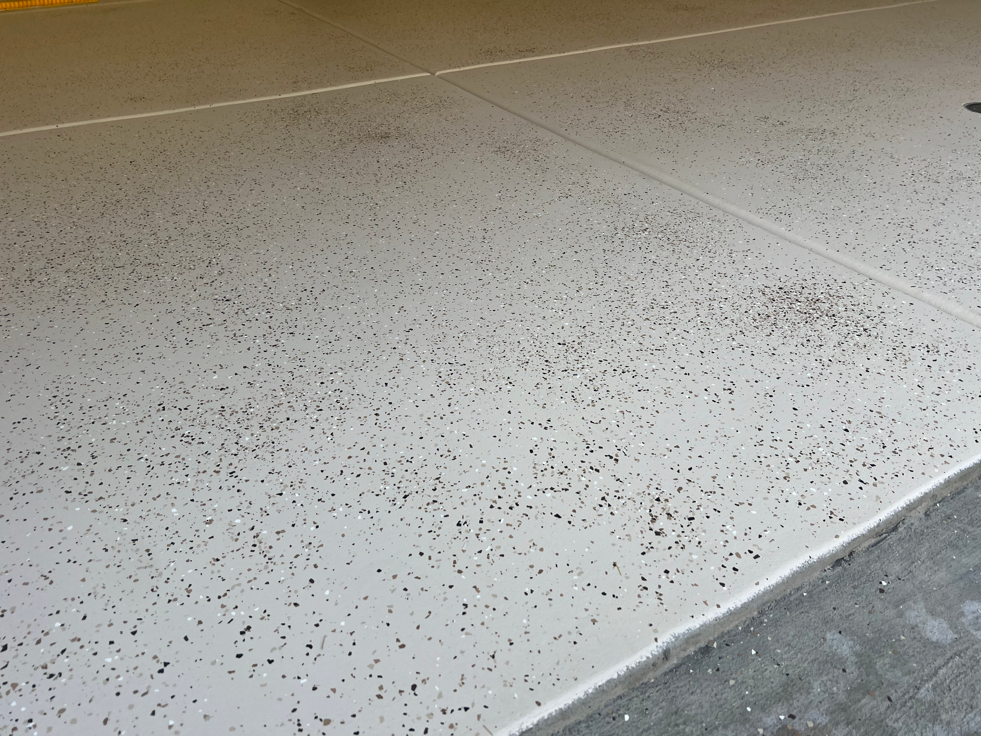 A newly-installed white epoxy garage floor with a speckled pattern on it.