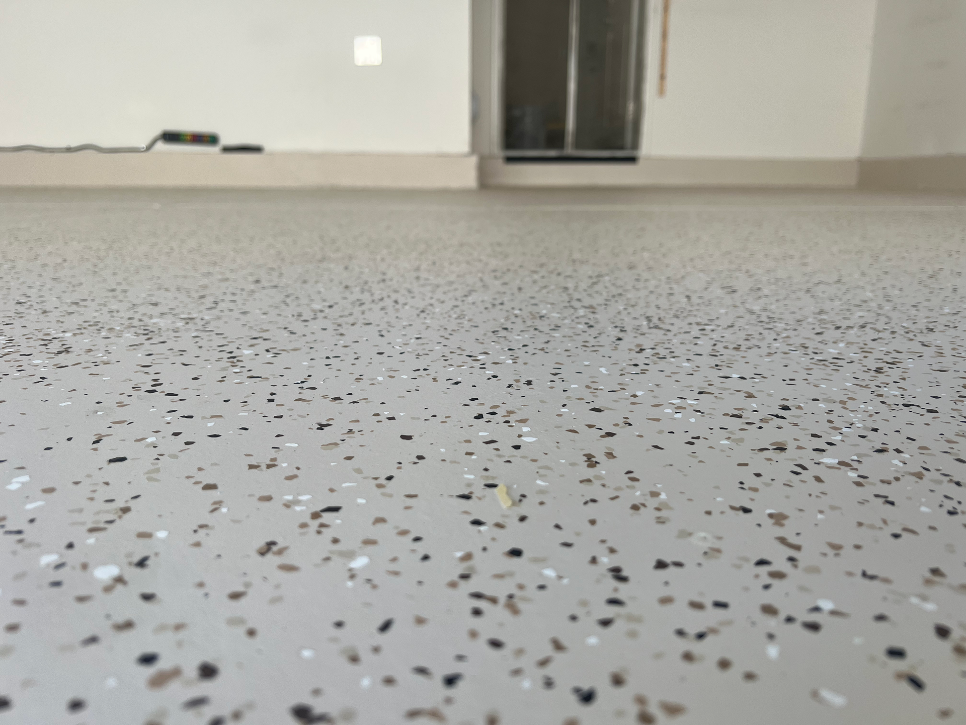 Garage floor with speckled epoxy coating in gray, black, and white.