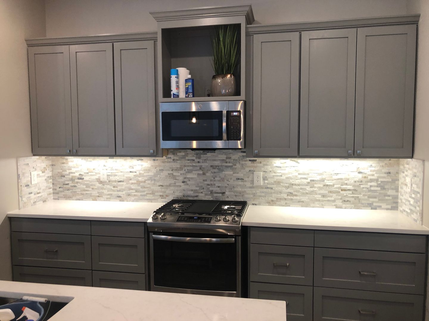 A kitchen with gray cabinets and stainless steel appliances