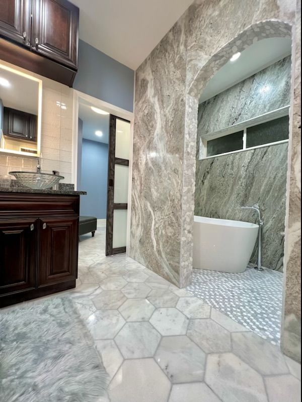 A bathroom with a tub , sink and mirror.
