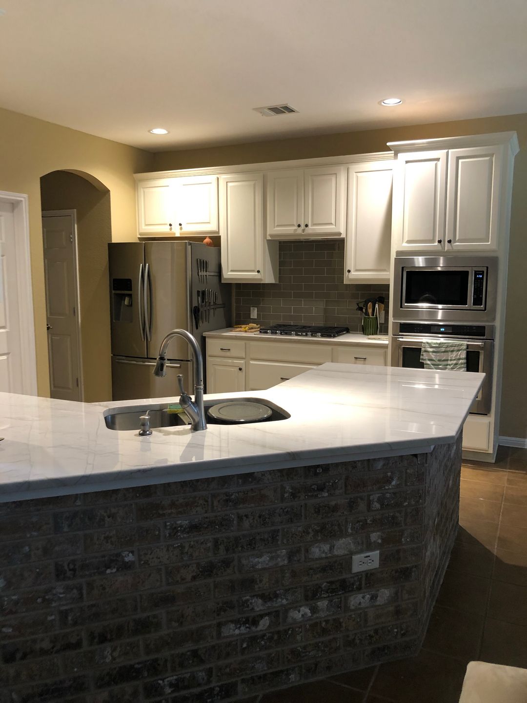 A kitchen with white cabinets and a brick counter top