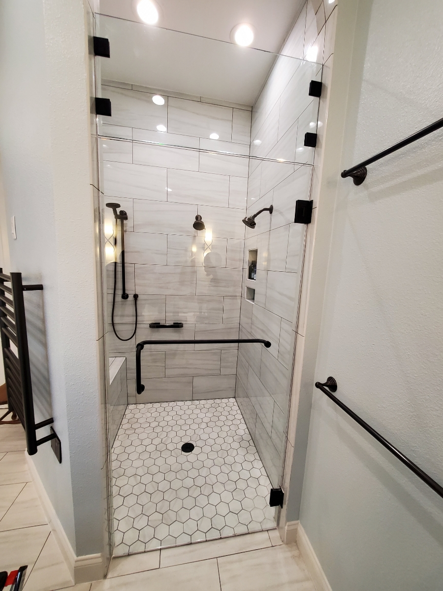 A bathroom with a walk in shower with a glass door