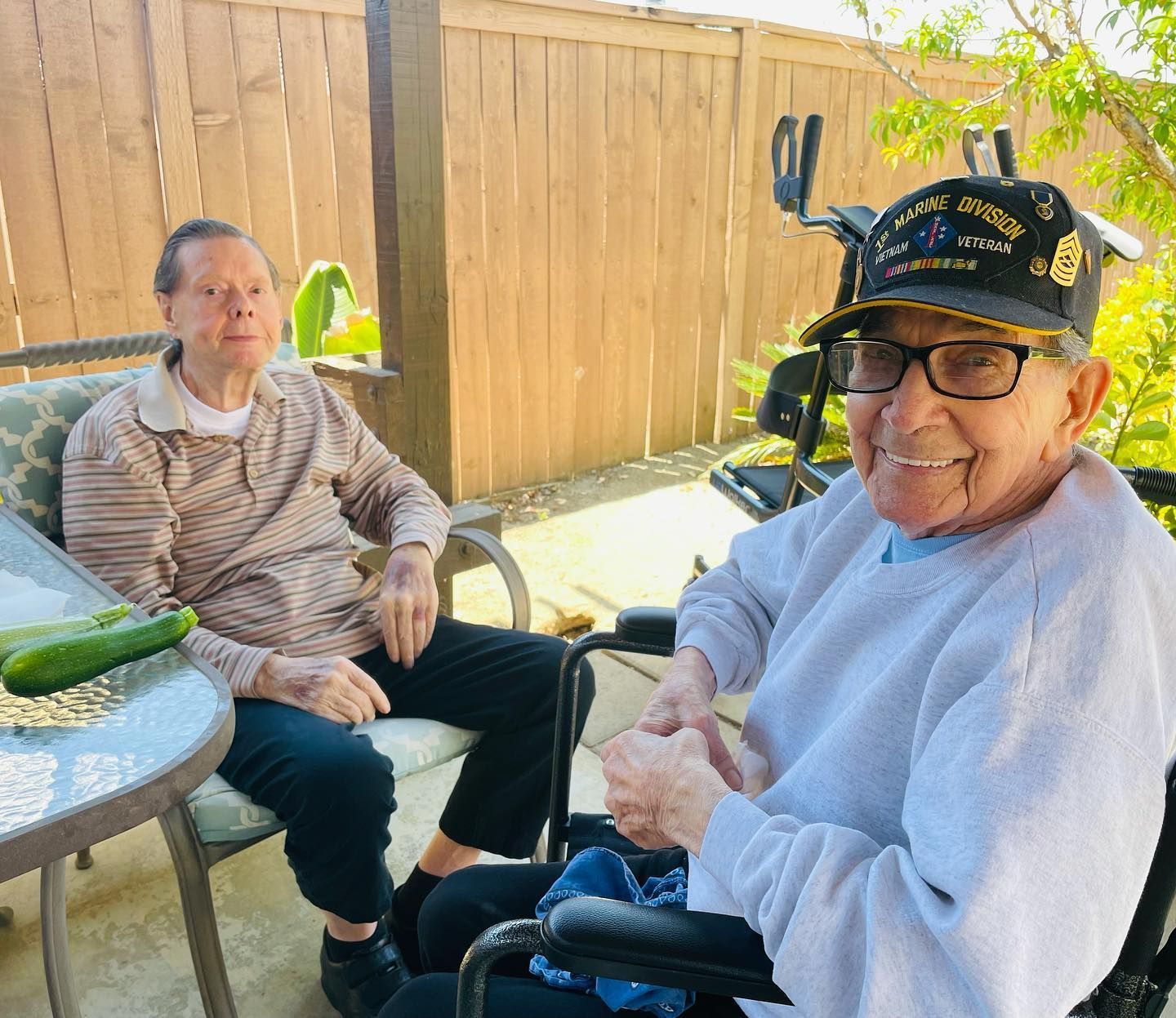 A man in a wheelchair is sitting next to another man in a chair.