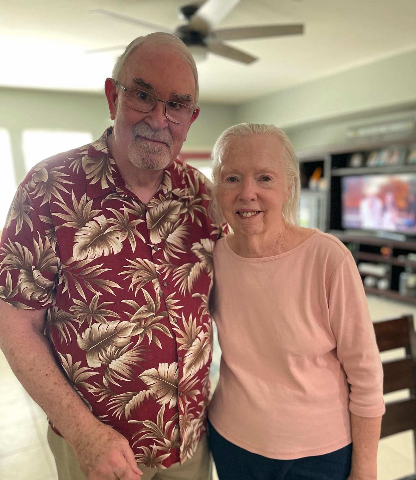 A man and a woman are posing for a picture in a living room.