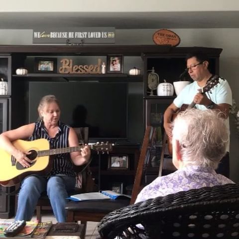 A man and a woman are playing guitars in a living room
