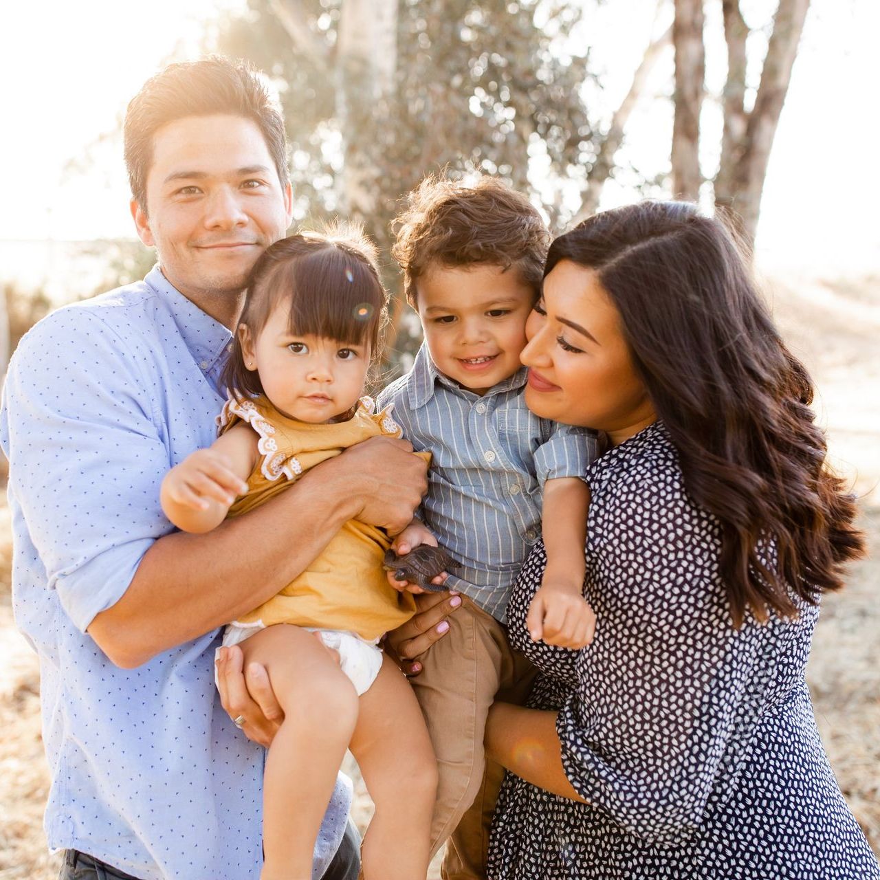 A family is posing for a picture together and the woman is holding a baby