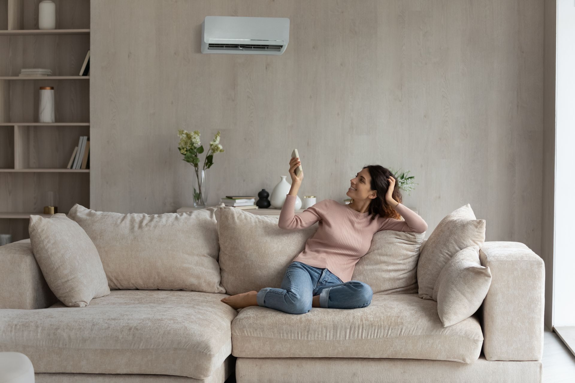 Woman lounging on a beige sofa in a modern living room, looking at her phone