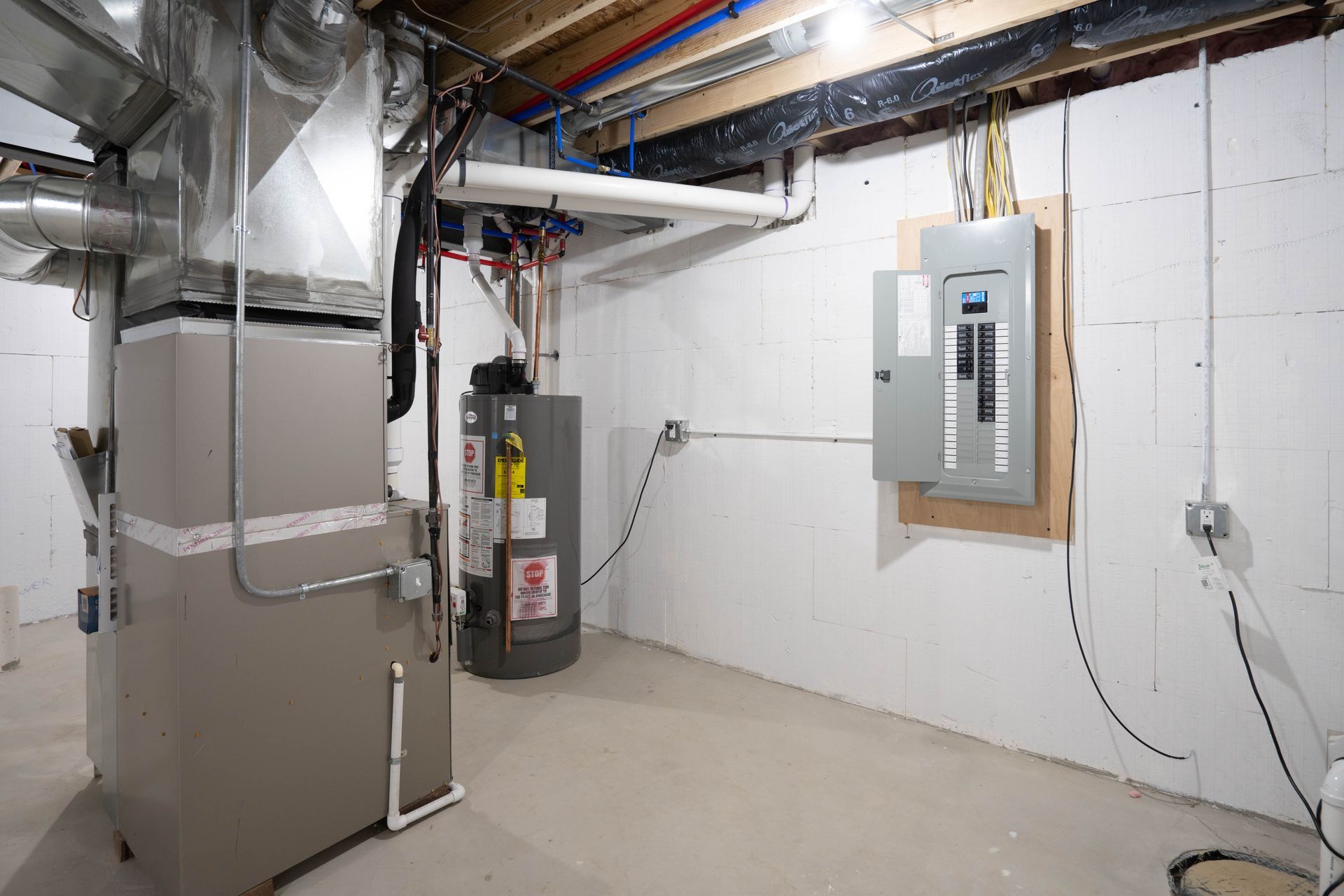 Basement utility room with furnace, water heater, and electrical panel along unfinished walls.