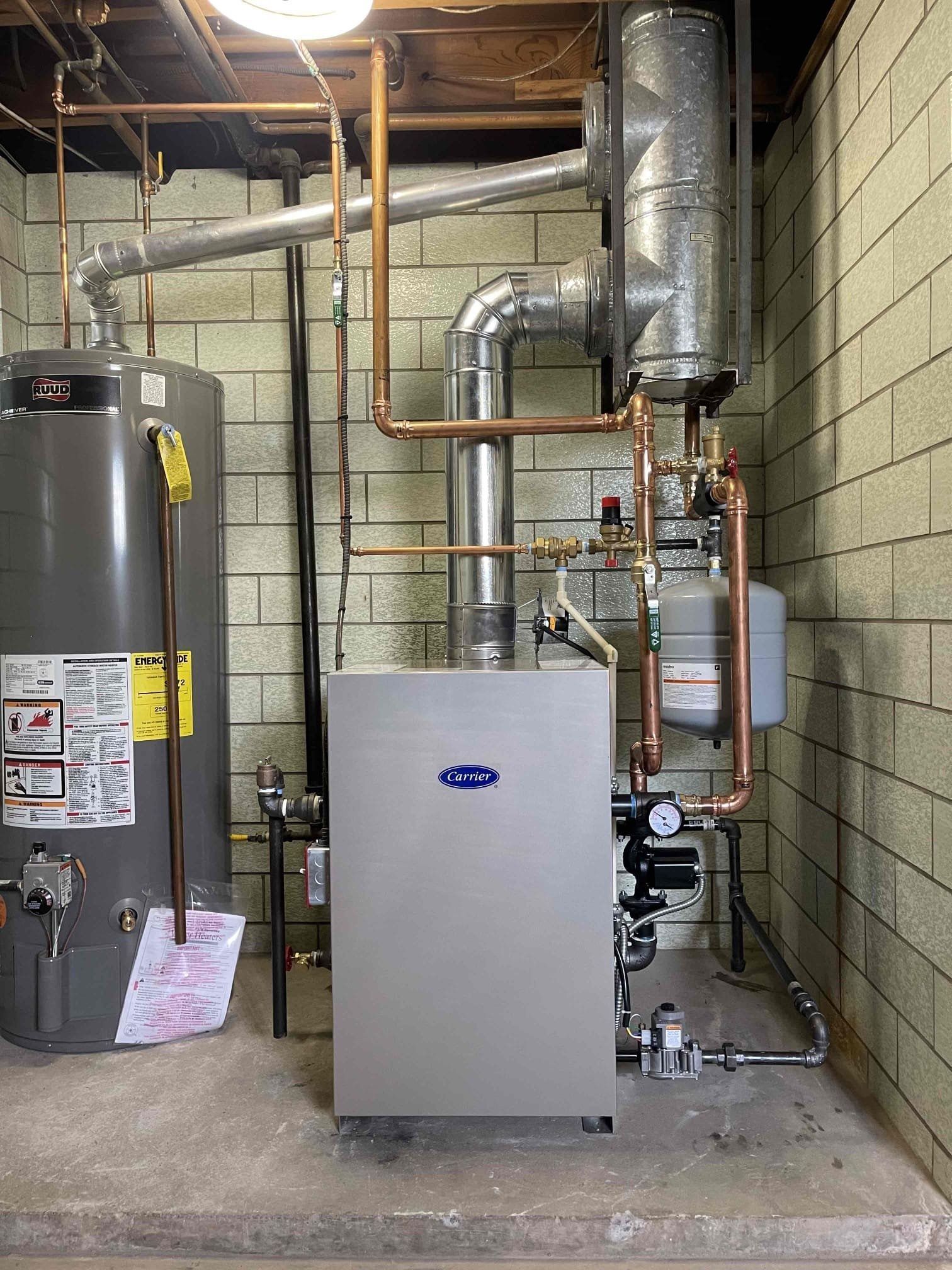 A water heater is sitting in a basement next to a boiler.