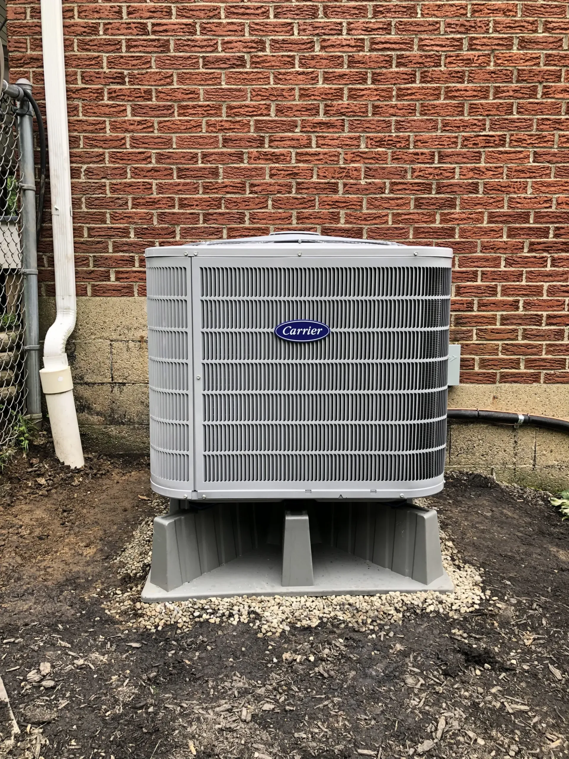 a carrier heat pump is sitting in front of a brick building .