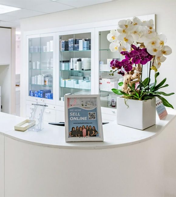 Bright white reception counter with orchids and a “Sell Online” sign in a clean office lobby