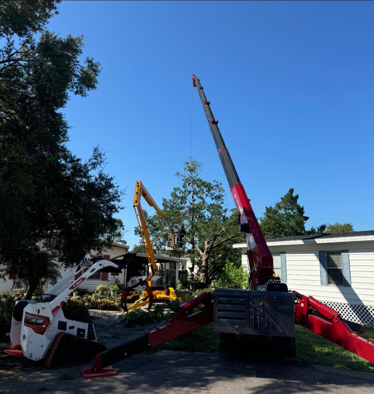 A red crane is sitting in front of a white house