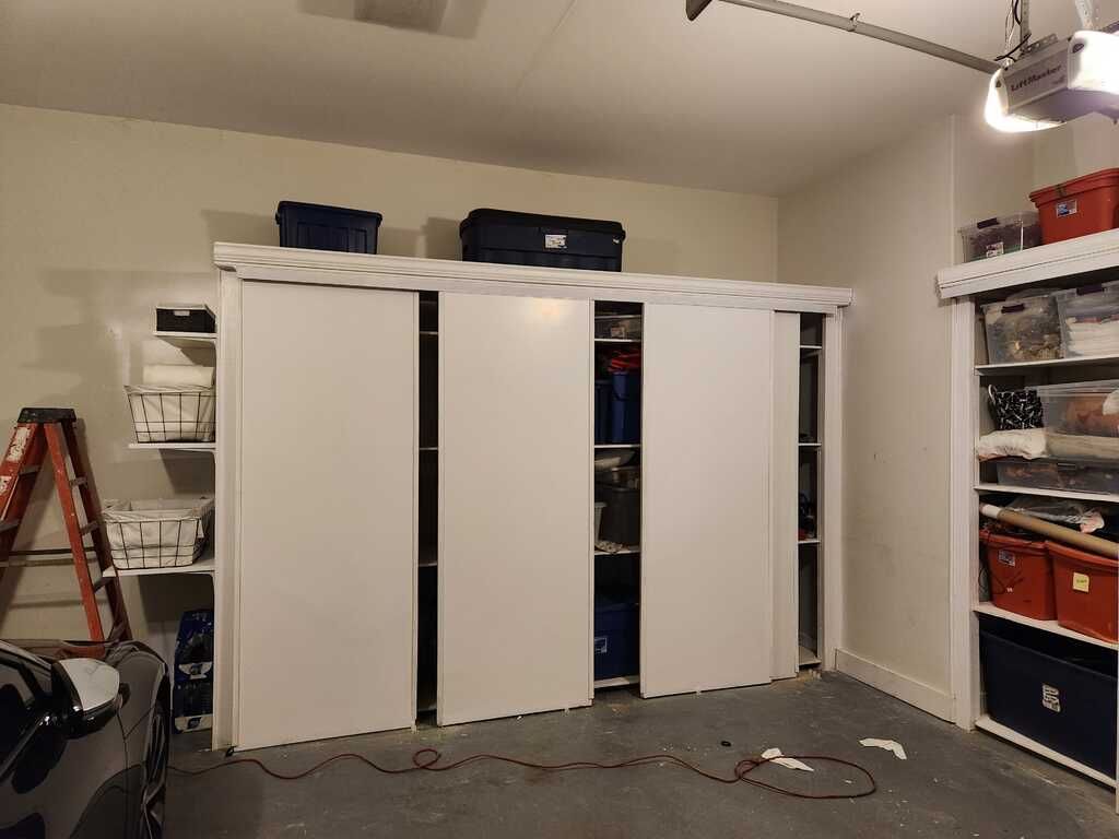 A garage with sliding doors , shelves , and a ladder.