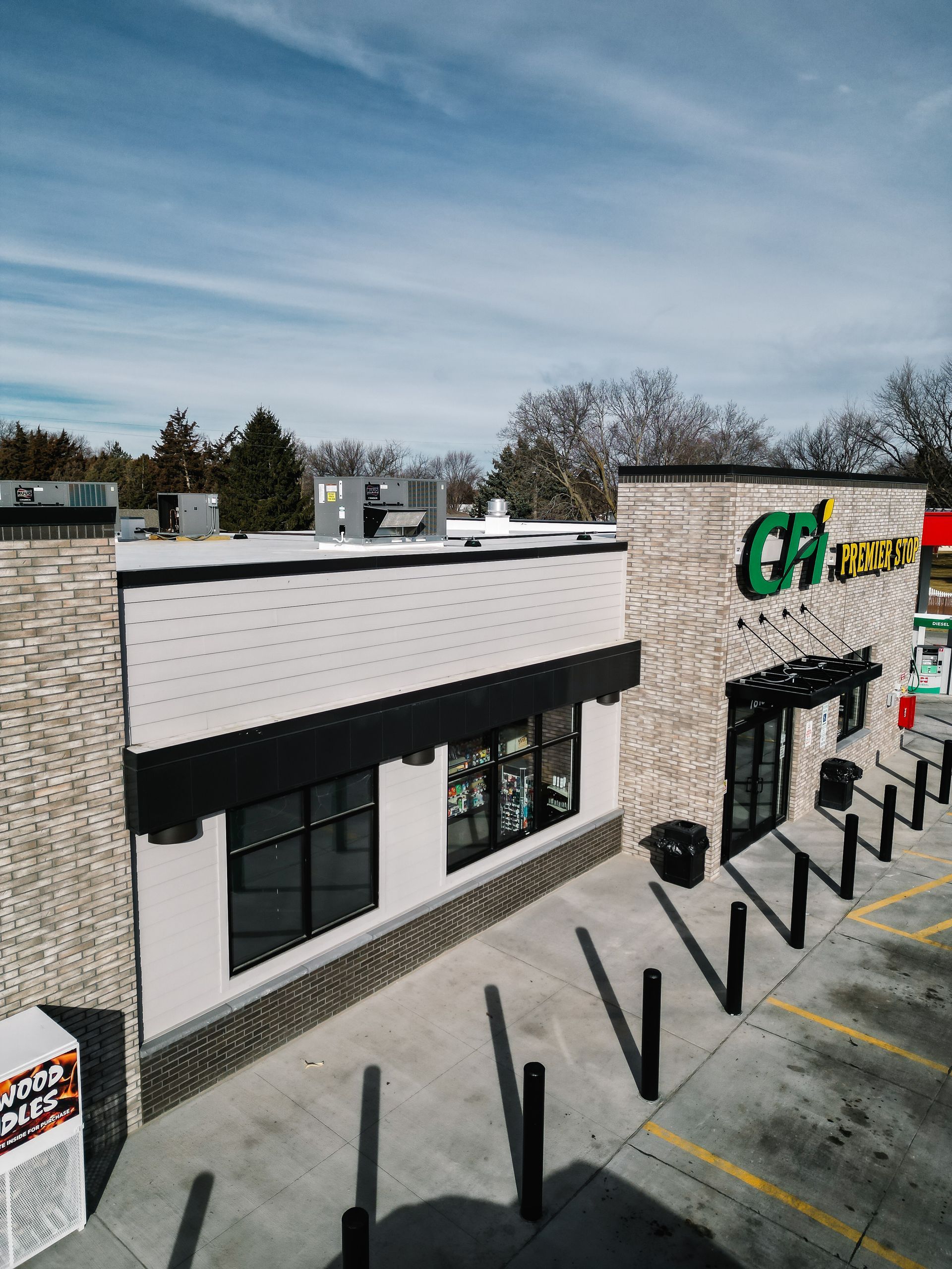 Strip-mall storefront with black awning, green-and-yellow sign, and empty parking spaces
