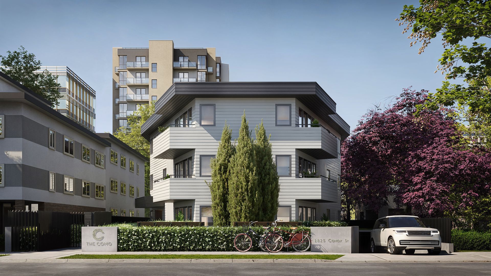 Modern apartment building with balconies, trees, and parked cars on a sunny day.