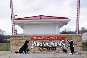 Purina Farms entrance sign with dog and cat silhouettes, red and white gate. 