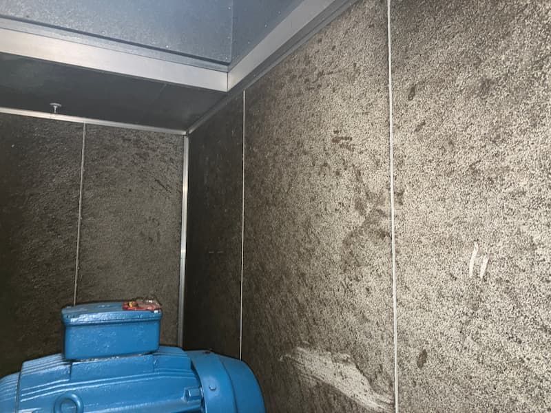 Inside of a gray-walled machinery room with a blue motor and metal trim.